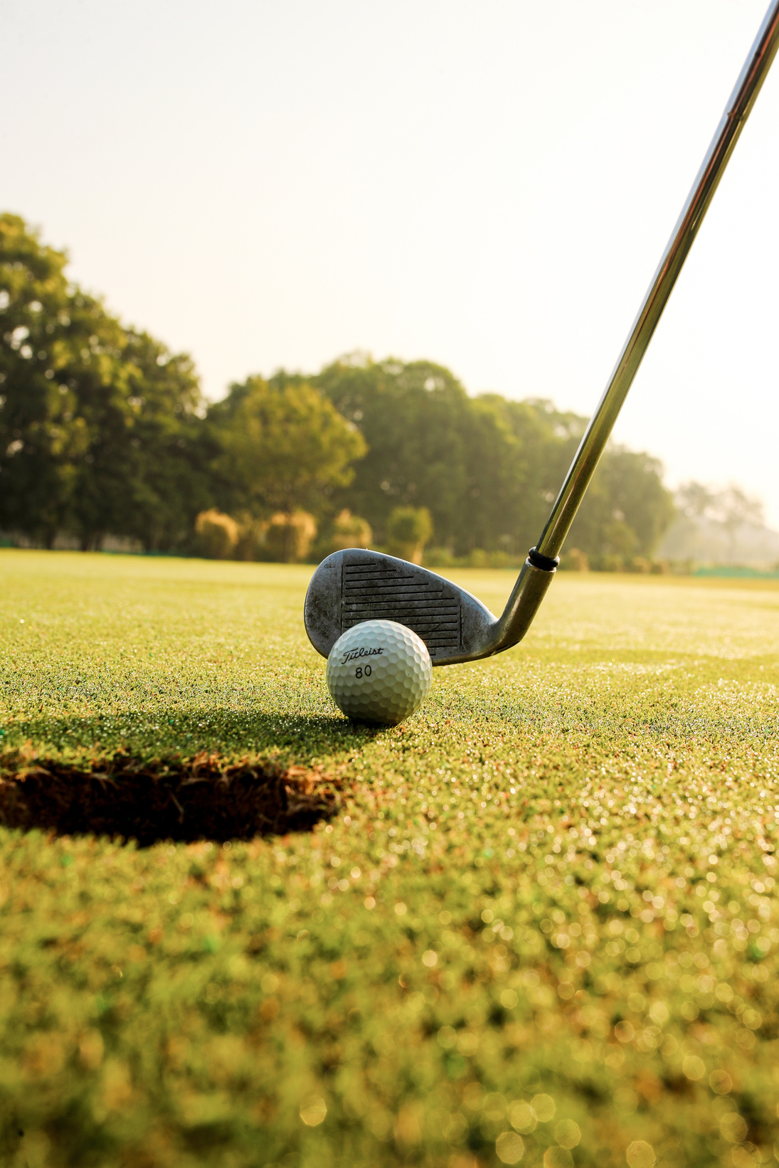 Golf club hitting ball on field